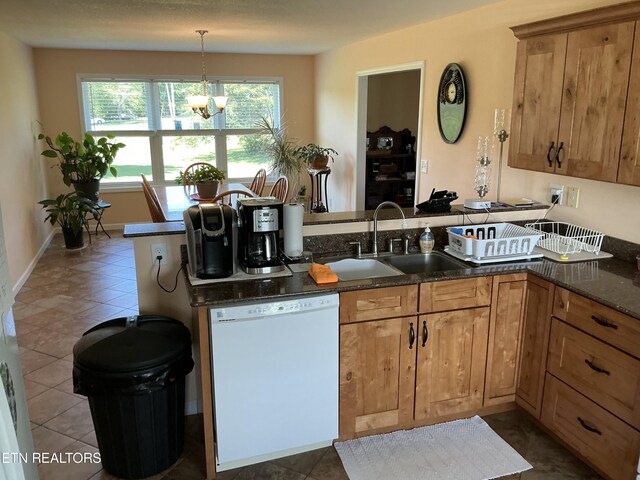 kitchen featuring sink, kitchen peninsula, dishwasher, a notable chandelier, and dark stone counters