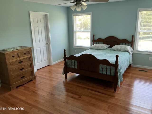 bedroom featuring ceiling fan, hardwood / wood-style floors, and multiple windows