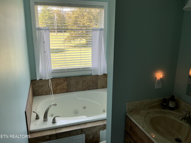 bathroom with vanity, tiled bath, and a healthy amount of sunlight