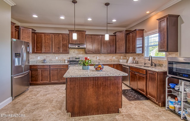 kitchen with sink, light stone counters, appliances with stainless steel finishes, decorative light fixtures, and a center island