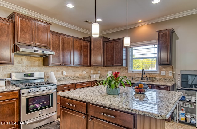 kitchen with sink, appliances with stainless steel finishes, decorative light fixtures, crown molding, and a center island