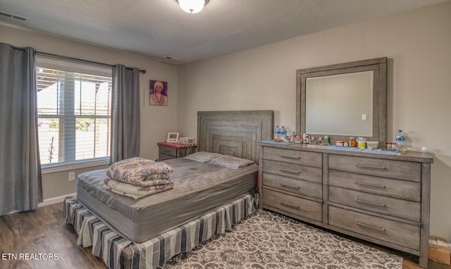 bedroom with dark hardwood / wood-style floors and a textured ceiling