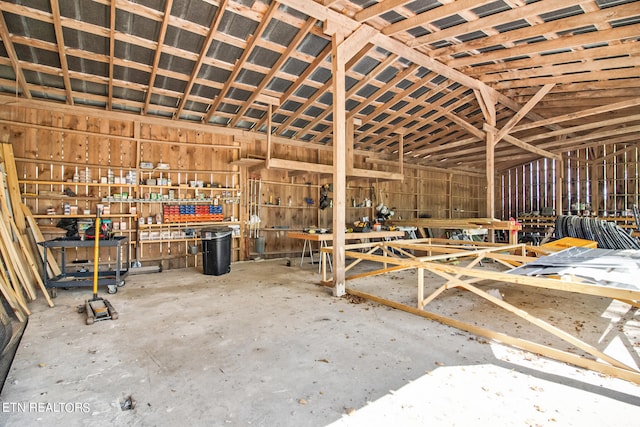 miscellaneous room featuring concrete flooring, lofted ceiling, and a workshop area