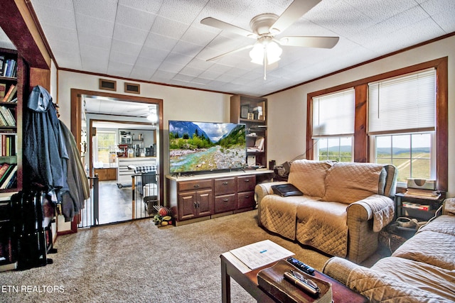 living room featuring carpet flooring, ornamental molding, and ceiling fan