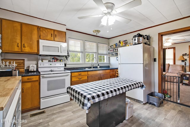 kitchen featuring white appliances, light wood-type flooring, crown molding, ceiling fan, and sink