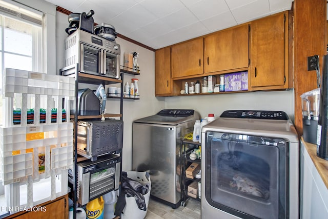 laundry area featuring separate washer and dryer, cabinets, light hardwood / wood-style flooring, and ornamental molding