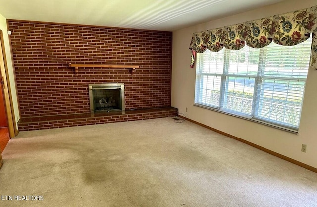 unfurnished living room with brick wall, carpet flooring, and a brick fireplace