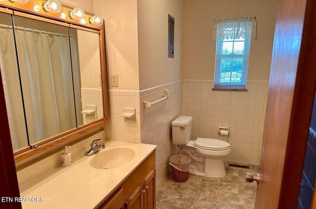 bathroom with tile walls, vanity, and toilet