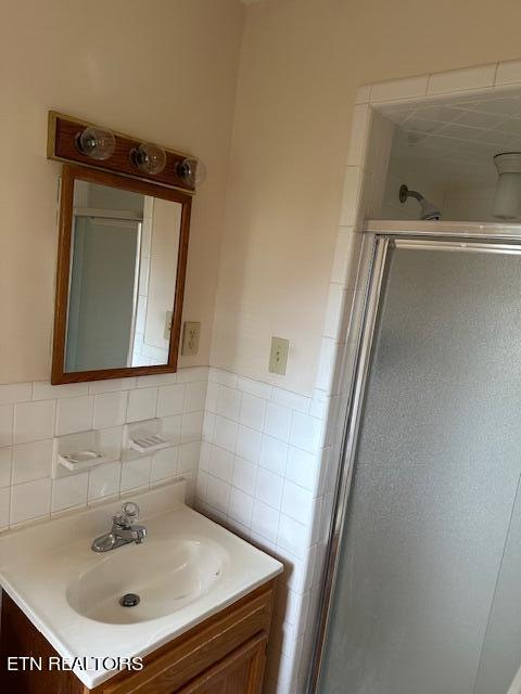 bathroom featuring an enclosed shower, vanity, and tasteful backsplash