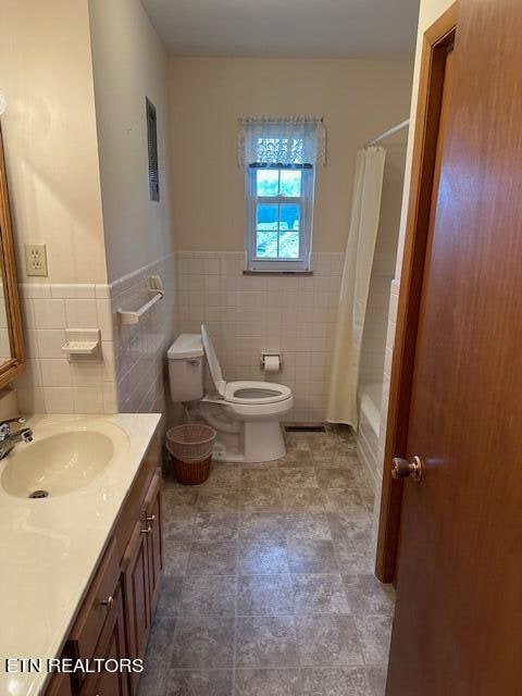 full bathroom with tile walls, vanity, toilet, and shower / bath combo with shower curtain