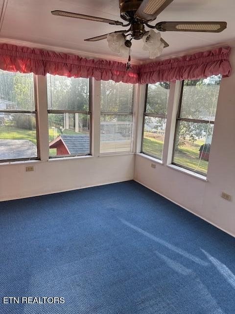 unfurnished sunroom with ceiling fan