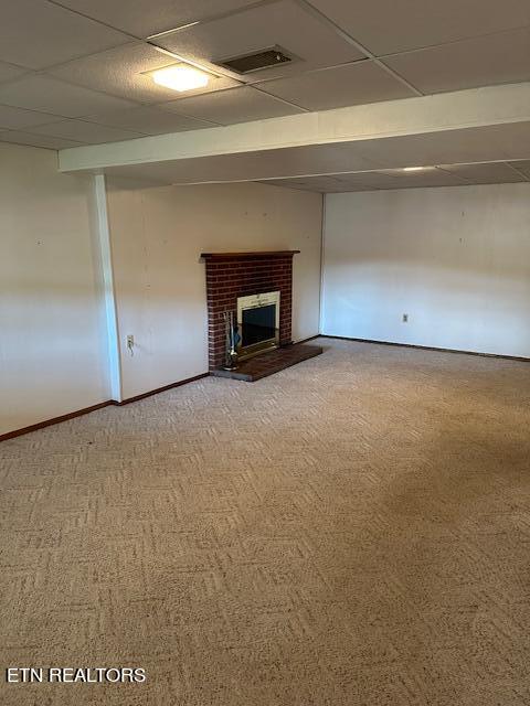 unfurnished living room featuring a paneled ceiling, carpet flooring, and a fireplace