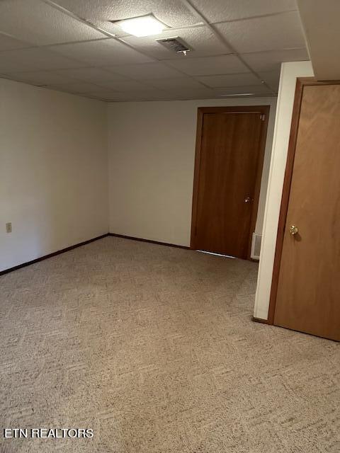 carpeted spare room featuring a paneled ceiling