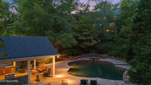 pool at dusk with a patio and a hot tub