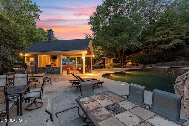 pool at dusk with a patio area