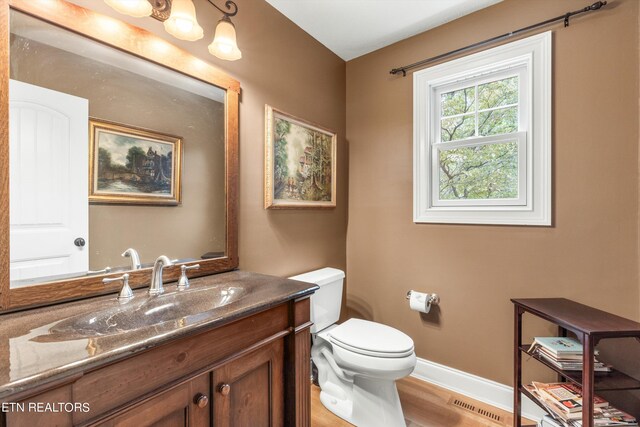 bathroom featuring wood-type flooring, vanity, and toilet