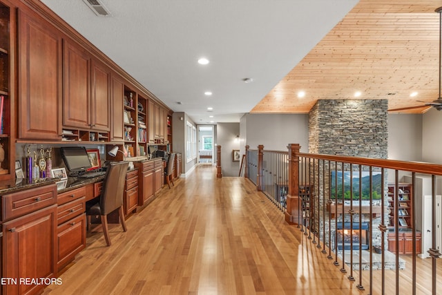 home office featuring ceiling fan, light hardwood / wood-style flooring, built in desk, and a wealth of natural light