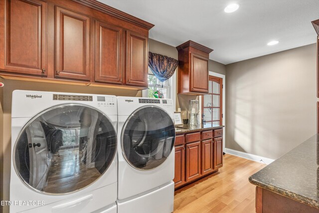 washroom with cabinets, light hardwood / wood-style floors, and washer and dryer