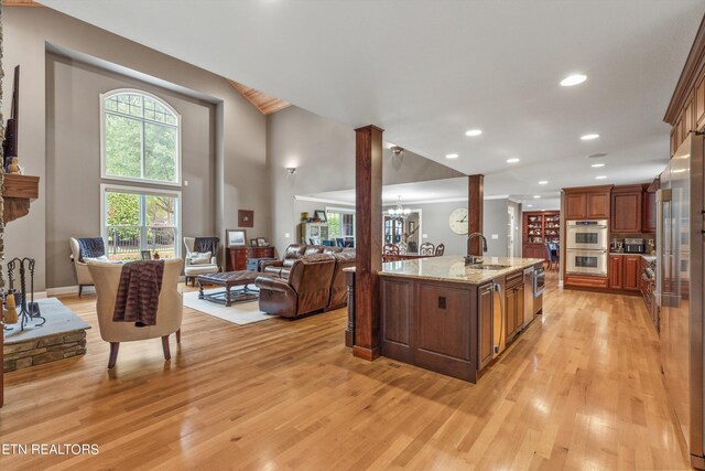 kitchen featuring a kitchen island with sink, sink, light hardwood / wood-style flooring, stainless steel appliances, and light stone countertops