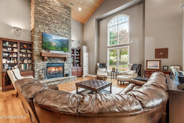 living room with a fireplace, light wood-type flooring, wood ceiling, and high vaulted ceiling