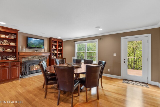 dining area with a healthy amount of sunlight, light hardwood / wood-style flooring, and a fireplace