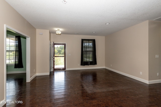 unfurnished room featuring a textured ceiling and dark hardwood / wood-style flooring