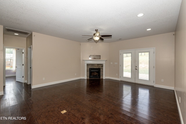 unfurnished living room featuring a tiled fireplace, dark hardwood / wood-style floors, ceiling fan, and a wealth of natural light