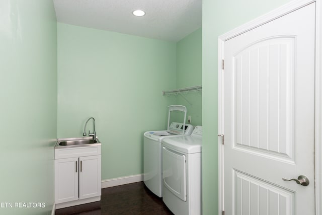 laundry room featuring sink, a textured ceiling, dark wood-type flooring, washer and clothes dryer, and cabinets