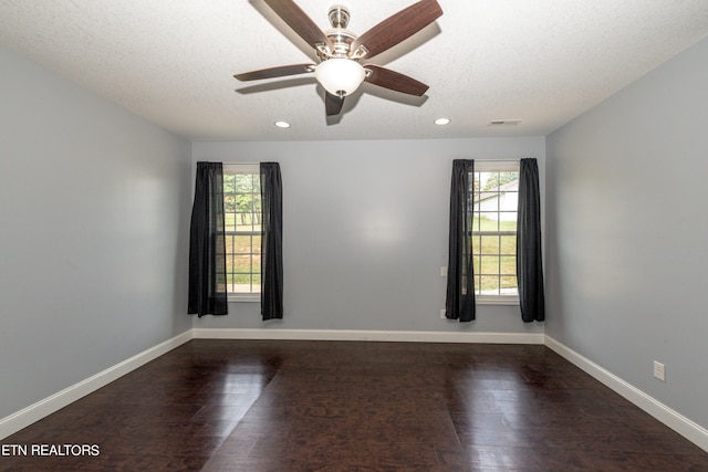 spare room featuring ceiling fan, dark hardwood / wood-style floors, plenty of natural light, and a textured ceiling