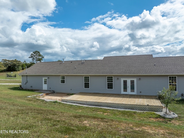 back of property with a wooden deck, french doors, and a lawn