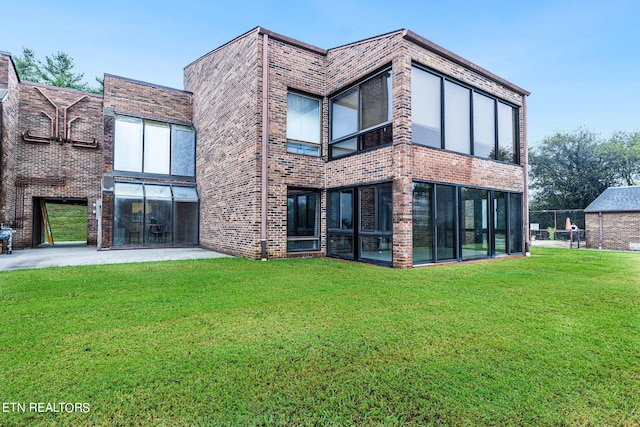 rear view of house with a sunroom and a lawn