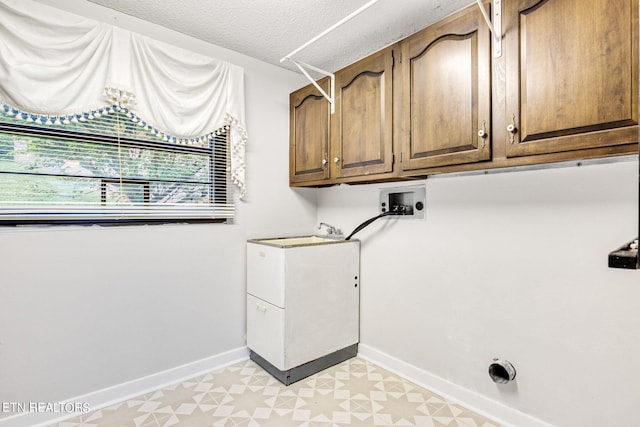 laundry area with washer hookup, cabinets, and a textured ceiling