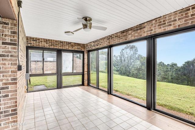 unfurnished sunroom featuring ceiling fan and a healthy amount of sunlight