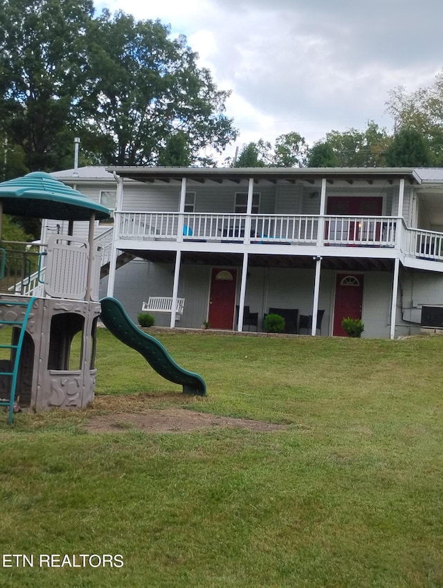 back of property with a lawn, a playground, and a deck