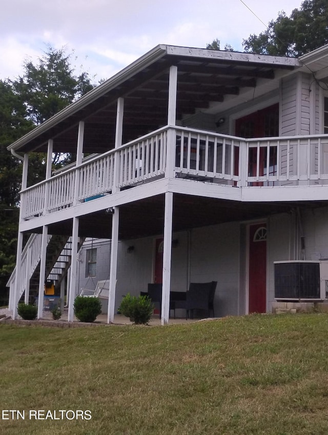 back of house with a deck and a lawn