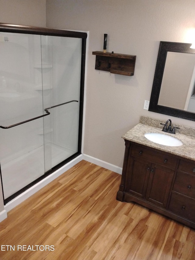 bathroom featuring wood-type flooring, vanity, and a shower with shower door