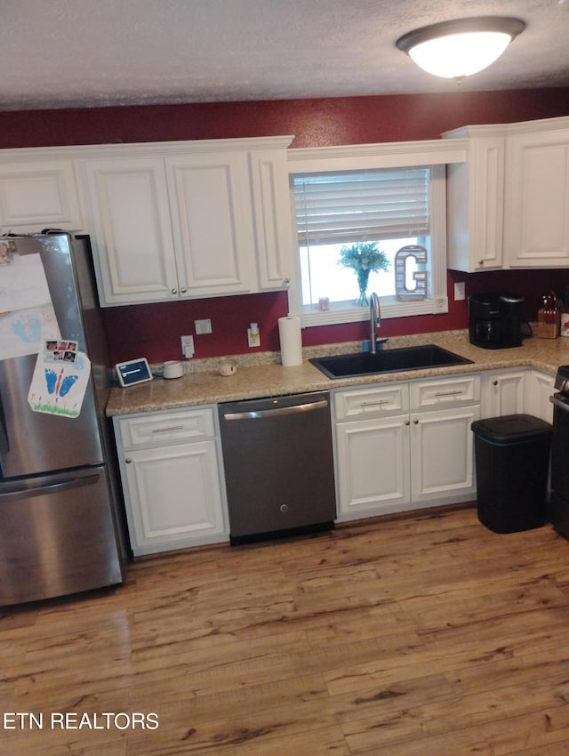 kitchen with light hardwood / wood-style flooring, white cabinetry, appliances with stainless steel finishes, and sink