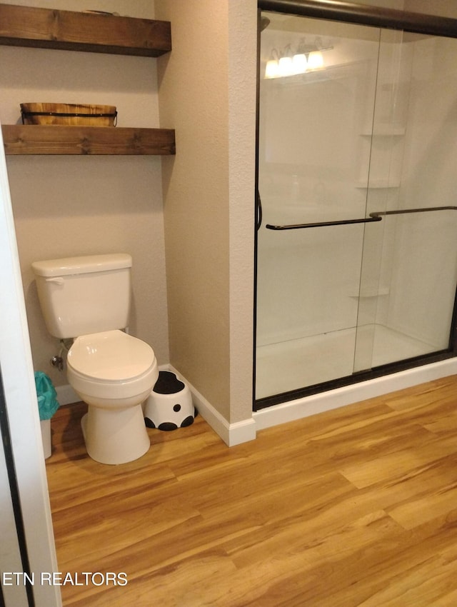 bathroom featuring toilet, hardwood / wood-style floors, and a shower with shower door