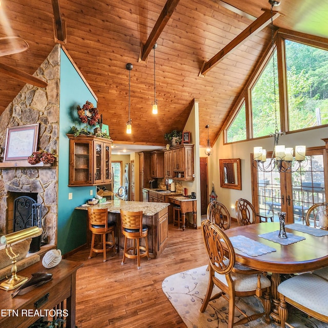 dining area with beamed ceiling, a fireplace, light hardwood / wood-style floors, and high vaulted ceiling