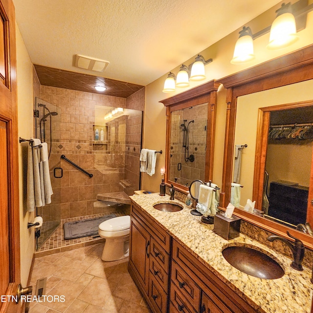 bathroom with a textured ceiling, vanity, toilet, and a shower with door