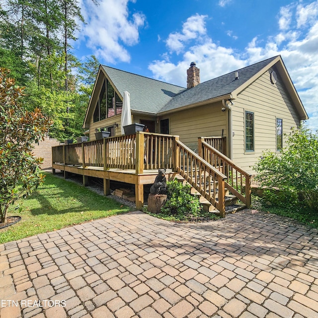 rear view of house featuring a wooden deck, a yard, and a patio