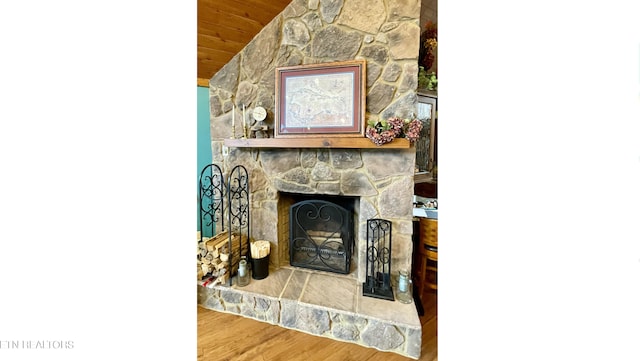 living room featuring wood ceiling, a stone fireplace, and hardwood / wood-style floors