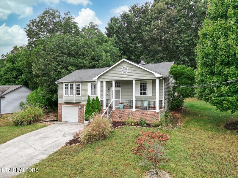 view of front of house with a front lawn, covered porch, and a garage