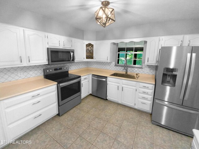 kitchen featuring sink, white cabinets, stainless steel appliances, backsplash, and light tile patterned floors