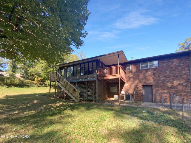 rear view of property featuring a yard, central air condition unit, and a wooden deck