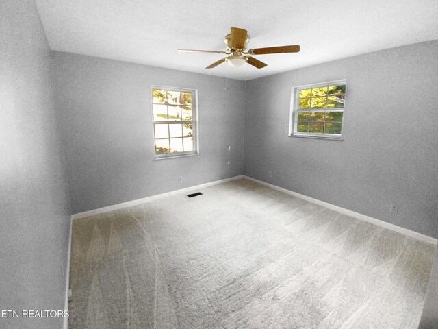 carpeted empty room featuring ceiling fan and a wealth of natural light