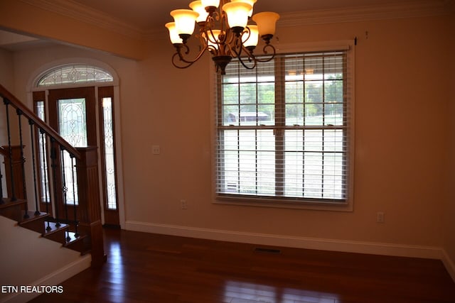 foyer featuring dark wood-type flooring, crown molding, and a chandelier