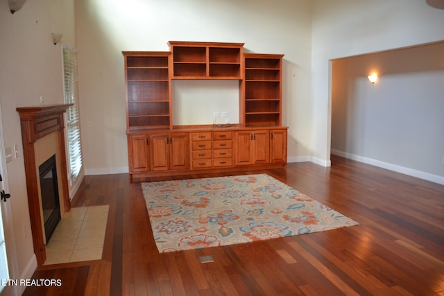 unfurnished living room featuring a tiled fireplace and dark wood-type flooring