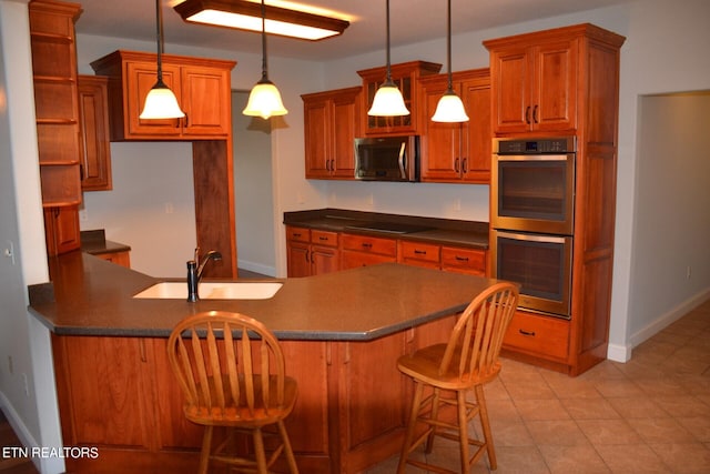 kitchen with sink, a kitchen bar, hanging light fixtures, appliances with stainless steel finishes, and light tile patterned floors