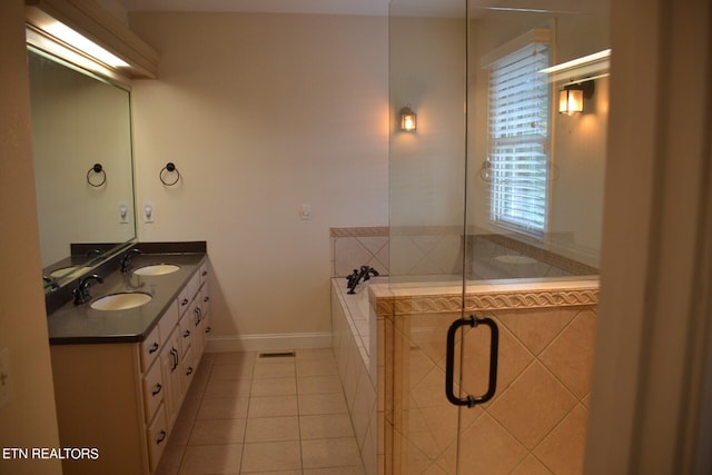 bathroom featuring tile patterned flooring, tiled bath, and vanity